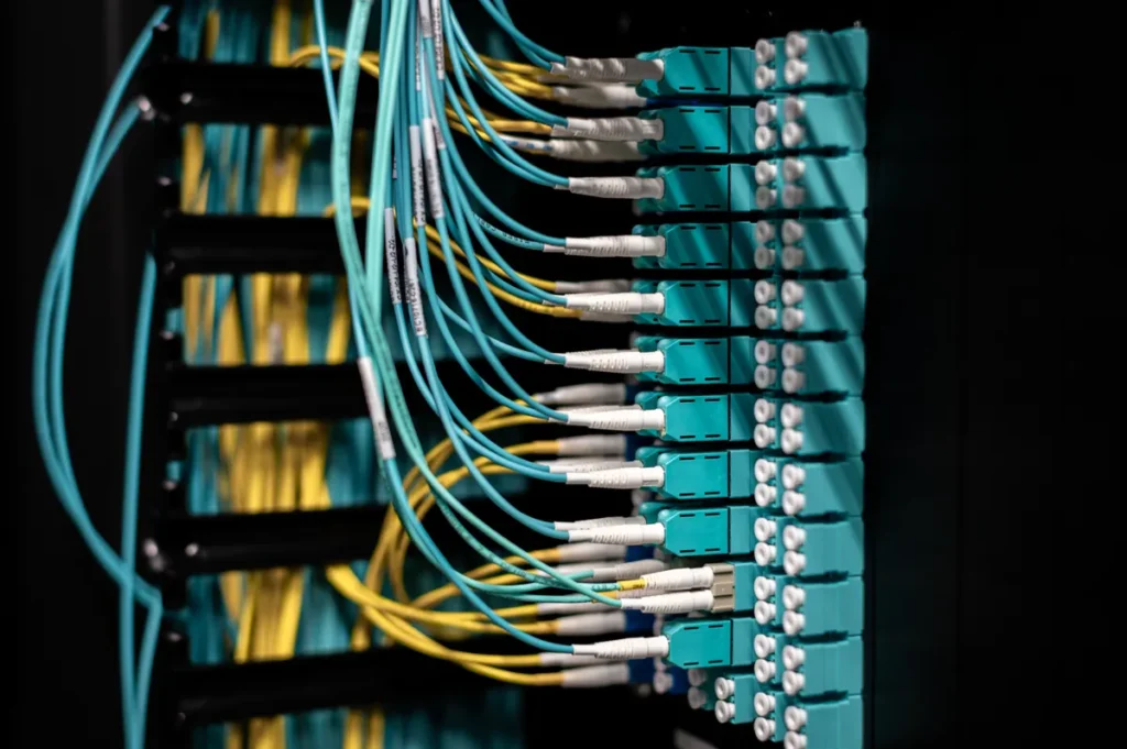 Intruder engineer weighs AI pentesting against human testers Closeup of switch in server with connectors and adapters connected to plastic device in dark room on blurred background insid