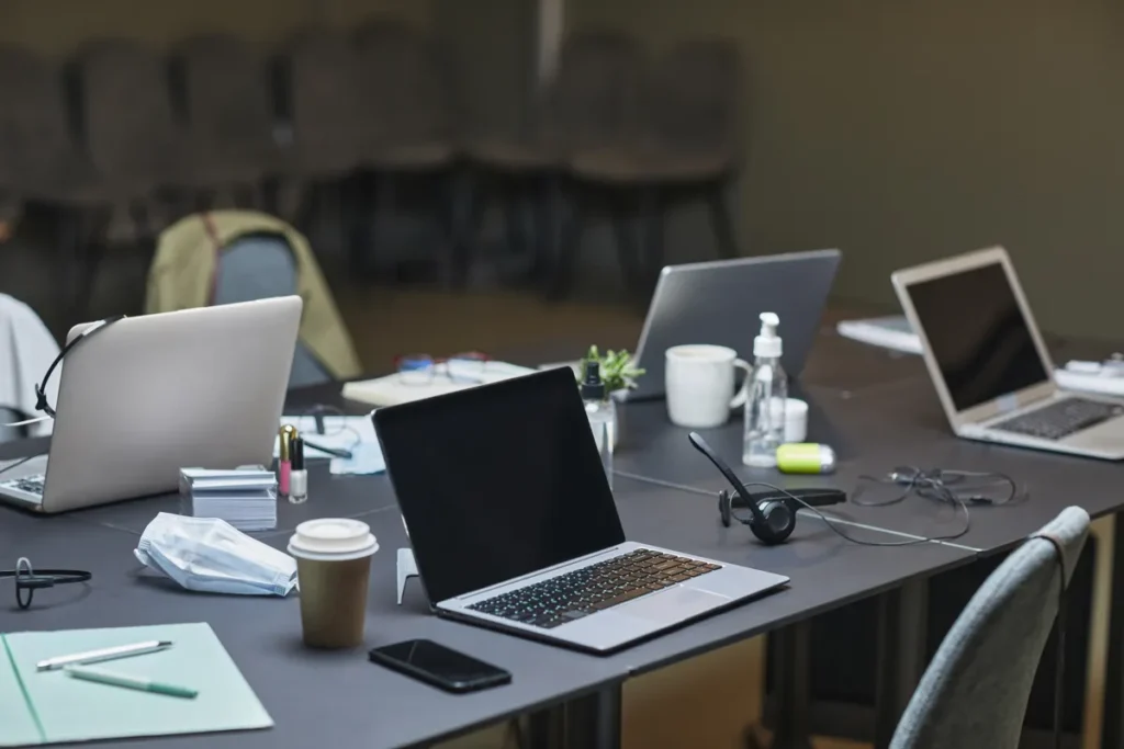 How IT admins should handle personal ChatGPT use on managed devices A cluttered office desk setup featuring multiple laptops, coffee cup, and office supplies for a busy workday